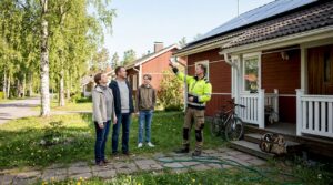 En familie og byggmester står sammen foran det miljøvennlige trehuset de har bygget.