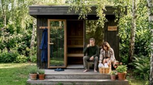 Ein Paar entspannt sich gemeinsam im Garten vor ihrem modernen Saunahaus.