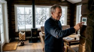 En eldre herremann justerer termostaten i den koselige tømmerhytta.