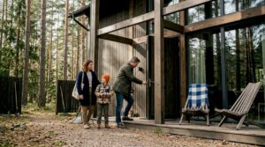 Eine Familie genießt gemeinsam die Zeit vor ihrer modernen Holzvilla im Grünen.